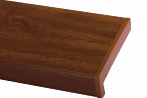 Zbliżenie na Parapet PVC o wzorze złotego dębu z wyraźnym usłojeniem i zaokrągloną krawędzią typu nosing, na jednolitym tle.