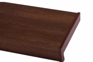 Zbliżenie ciemnego, lakierowanego parapetu PVC o wzorze orzechu z wyraźnym usłojeniem i zaokrągloną krawędzią typu bullnose.