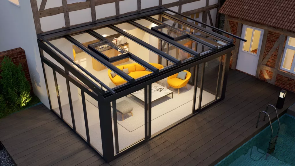 Nowoczesny ogród zimowy z czarną aluminiową konstrukcją i przeszklonym dachem, dobudowany do tradycyjnego domu; w środku żółta sofa i fotel, na zewnątrz drewniany taras przy basenie o zmierzchu.