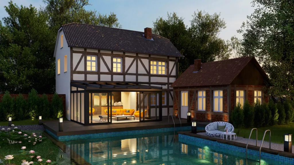 Wieczorem widoczny tradycyjny dom z muru pruskiego z nowoczesnym, przeszklonym ogrodem zimowym i jasnym salonem, obok mniejszej przybudówki, a na pierwszym planie podświetlany basen i ogród.