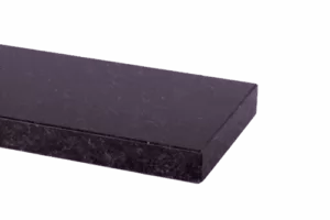 Zbliżenie na narożnik ciemnego, polerowanego parapetu kamiennej (granit) z drobnym nakrapianiem i fazowaną krawędzią, na jednolitym fioletowym tle.