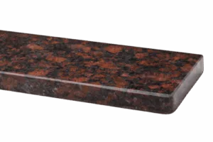 Polerowany parapet z czerwono‑czarnym granitem o łaciatym wzorze i zaokrąglonej krawędzi, pokazany na neutralnym tle.