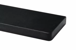 Zbliżenie czarnego, prostokątnego parapetu marmurowego o matowej powierzchni i zaokrąglonym narożniku na ciemnym tle.