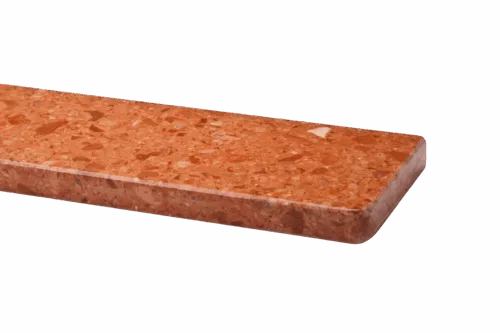 Zbliżenie na prostokątny, polerowany parapet marmurowy w ceglastym kolorze z plamistym wzorem, z zaokrągloną krawędzią.